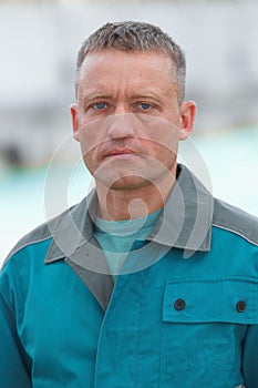 Portrait of a worker in uniform. A serious and focused Caucasian man in blue overalls with space for a layout