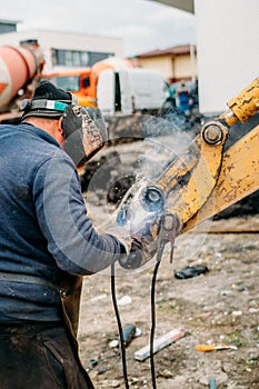 worker using arc welding machine for working on construction site