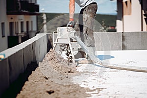 Portrait of worker using sand and cement pump, screed laying and finishing on construction site