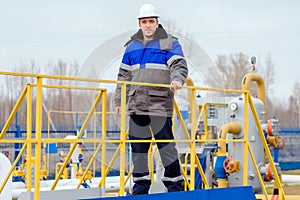 Portrait of worker in white helmet and winter pea jacket at industrial gas facility.