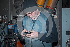 Portrait of a worker in a workshop with a mobile phone