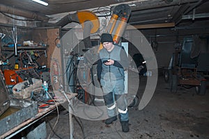 Portrait of a worker in a workshop with a mobile phone