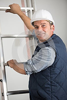 portrait workman with hands on rungs ladder
