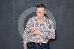 Portrait of worried alarmed man touching breast with hand