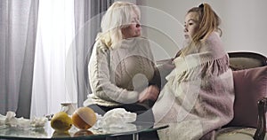Portrait of worried Caucasian blond woman hugging ill granddaughter. Wise mature grandmother taking care of sick girl at