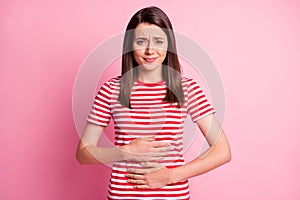 Portrait of worried girl touch her stomach suffer pms food poisoning wear casual style t-shirt isolated over pink color