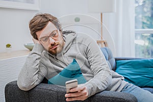 Portrait of worried man on the sofa holding cellphone at home