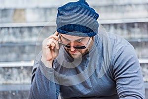 Portrait of a worried man with sunglasses talking on the phone