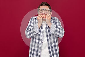 Portrait of worried nervous or stressed middle aged business man in casual checkered shirt and eyeglasses standing, bitting his