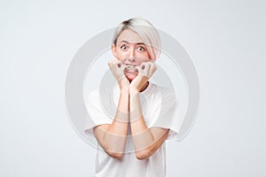 Portrait of worried scared woman with dyed short hair looking at camera, studio shot.