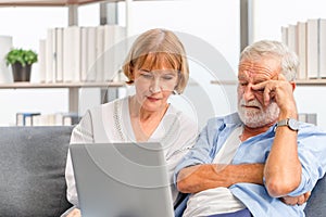 Portrait of Worried senior couple checking their bills and work on netbook read document information at home, Serious retired