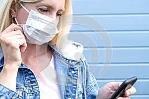 Portrait of worried woman in protective mask and using smartphone, busy young blond caucasian girl reading news about coronavirus