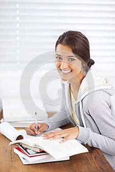 Portrait, writing and happy woman studying in college, learning and reading for school project at desk. Face, books and