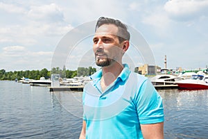 Portrait of yachtsman in marina background. Summer vacation yachting time for male lifestyle