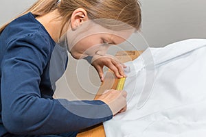 Girl is measuring a white textil with a yellow measuring tape photo