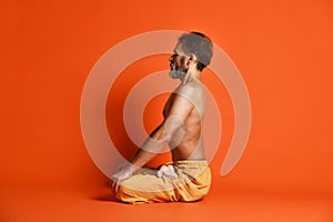 Portrait of yogi men doing yoga exercise on black mat, he breath and performing Upward abdominal lock, Uddiyana Bandha.