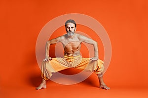 Portrait of yogi men doing yoga exercise on black mat, he breath and performing Upward abdominal lock, Uddiyana Bandha.