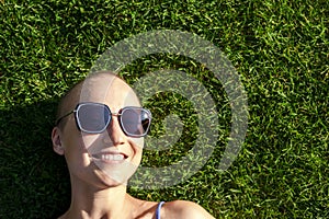 Portrait young adult bald shaved beautiful caucasian woman enjoy having fun lying on green grass lawn and smiling