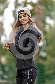 Portrait of a young adult blonde woman in sportswear and hat outdoors