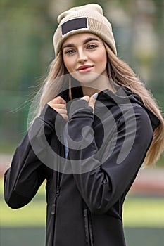 Portrait of a young adult blonde woman in sportswear and hat outdoors