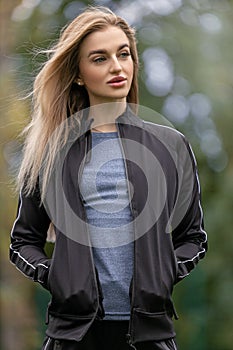 Portrait of a young adult blonde woman in sportswear outdoors
