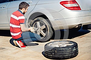 Portrait of young adult changing tyres and enjoying a sunny day