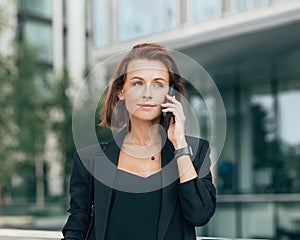 Portrait of a young adult female with ginger hair talking on a mobile phone while standing outdoors