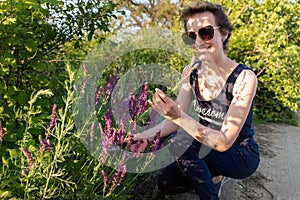 Portrait of young adult happy caucasian woman gathering harvest sage herbs wild flowers bouquet at meadow outdoors