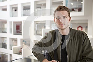 Portrait of young adult male student on mezzanine in university