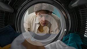 View from inside the washing machine, adult man looking inside the washer drum