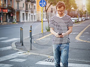 Portrait of young adult man crossing inattentively the street di