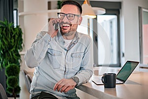 Portrait of young adult smiling cheerful businessman entrepreneur in office making a phone call