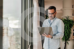 Portrait of young adult smiling cheerful businessman entrepreneur in office using laptop computer having online video call