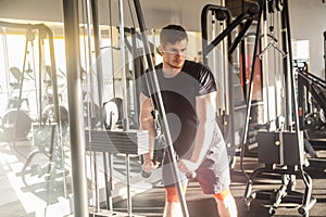 Portrait of young adult sport athlete man training at gym alone, standing and lifting weights in the gym, doing exercises for