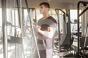 Portrait of young adult sport athlete man training at gym alone, standing and lifting weights in the gym, doing exercises for