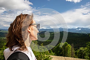 Portrait young adult woman enjoy adventure trekking looking over awesome mountain forest panoramic view with blue sky