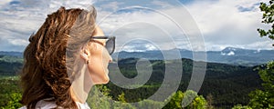 Portrait young adult woman enjoy adventure trekking looking over awesome mountain forest panoramic view with blue sky