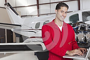 Portrait of young aeronautic engineer standing in front of an airplane propeller