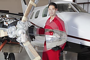 Portrait of young aeronautic engineer standing in front of an airplane propeller