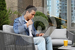 Portrait of  young African-American man with laptop in outdoor cafe