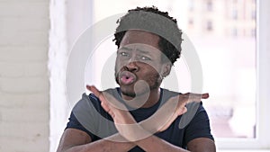 Portrait of Young African American Man saying No by Hand Gesture