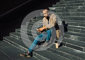 Portrait of young african american man sitting on steps using mobile