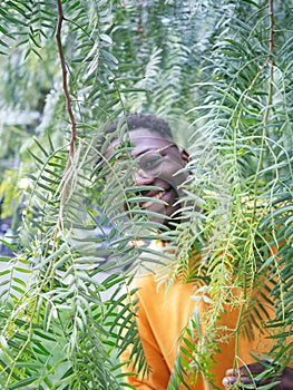 Portrait of a young African American man smiling behind vegetation. Artistic Portrait