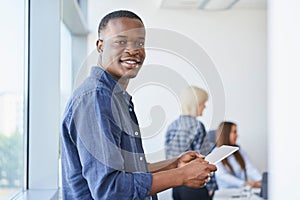 Portrait of young African American man standing with digital tablet in coworking office