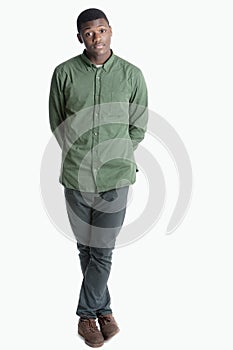 Portrait of a young African American man standing with legs crossed over gray background