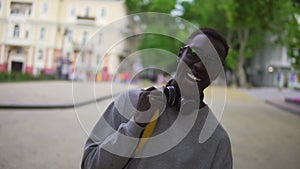 Portrait of young african american man in stylish glasses and headphones looking at camera smile feel happy. Put on his