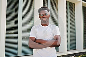 Portrait of young african american serious confident guy looking at camera with crossed arms standing outside. Handsome