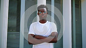 Portrait of young african american serious confident guy looking at camera with crossed arms standing outside. Handsome