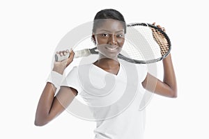 Portrait of young African American woman holding racket over white background