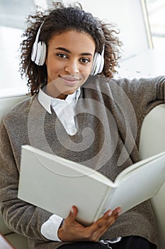 Portrait of young african american woman reading book on sofa in cafe